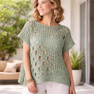 May include: A light green, open-weave crochet top with short sleeves. The top features a round neckline and a loose, flowing fit. The crochet design includes decorative openwork patterns. The model is wearing white shorts.