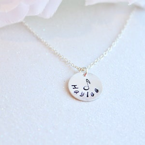 May include: Silver necklace with a round pendant featuring the name "Haylee" and a musical note.