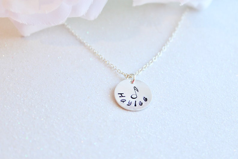 May include: Silver necklace with a round pendant featuring the name "Haylee" and a musical note.