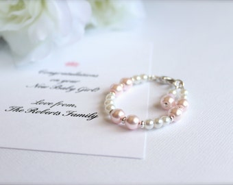 May include: A white and pink beaded bracelet with a silver clasp. The bracelet is on a white card with the text "Congratulations on your New Baby Girl Love from The Roberts Family".