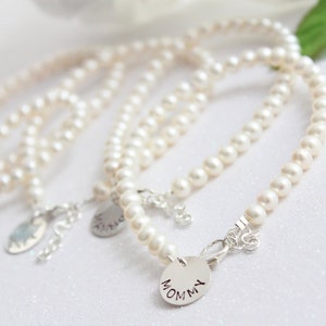 May include: Set of four pearl bracelets with silver charms. The charms are engraved with the words "Mommy", "Sister", "Friend", and "Love".