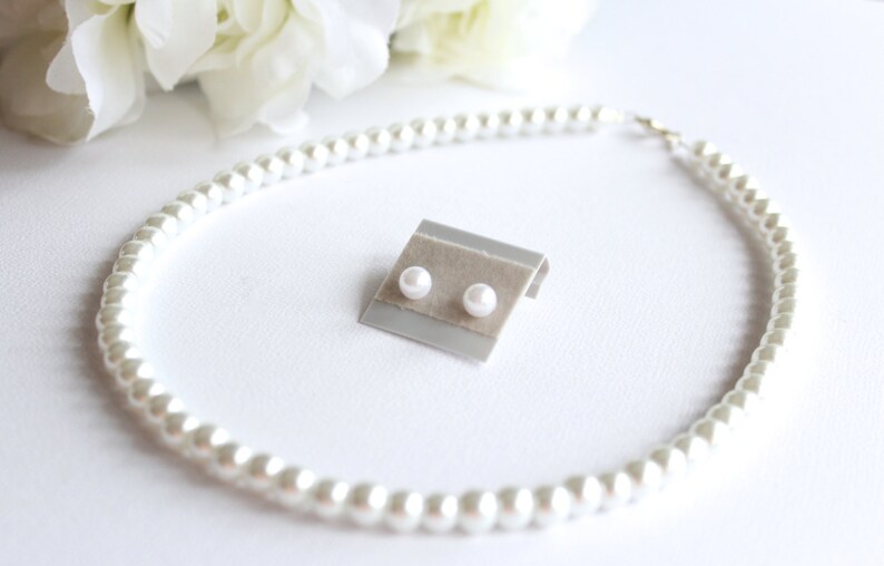 Puede incluir: Un conjunto de pendientes de perlas y un collar de perlas. Los pendientes est&aacute;n en una peque&ntilde;a tarjeta de exhibici&oacute;n. El collar est&aacute; hecho de perlas blancas y est&aacute; dispuesto en c&iacute;rculo.