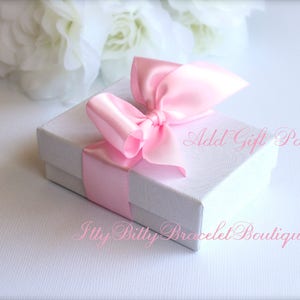 May include: A white gift box with a pink satin ribbon bow. The box is tied with a pink ribbon and has the text "Add Gift Packaging" printed on the top. The text "Itty Bitty Bracelet Boutique.com" is printed on the bottom of the box.