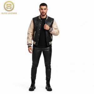 May include: Black leather varsity jacket with cream-colored sleeves and black and white striped cuffs and hem. The jacket has a black collar and a black front with a logo. The model is wearing black leather pants and black boots.