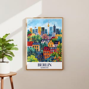 May include: A framed art print showing a vibrant illustration of Berlin, Germany. The artwork portrays a cityscape with buildings, trees, and a blue sky. The words "BERLIN" and "GERMANY" are printed at the bottom of the print.
