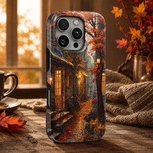 Puede incluir: Una funda para smartphone con una ilustración detallada de una calle estrecha de adoquines bordeada por edificios de piedra, faroles brillantes y árboles de otoño con follaje naranja y rojo vibrante, sobre un fondo oscuro y texturizado.