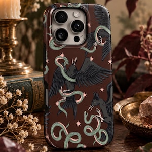 May include: A dark brown smartphone case featuring a repeating pattern of black birds with open beaks and light green snakes intertwined with them, accented by small pink four-pointed stars scattered across the surface of the protective cover.