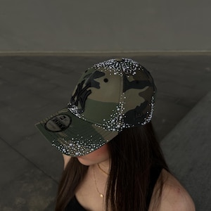 Op de afbeelding: Een baseballpet met camouflageprint, voorzien van een zwart New York Yankees-logo aan de voorzijde en een 9FORTY-sticker op de klep. De pet is versierd met talloze kleine witte imitatieparels die over de bol en de gebogen klep zijn verspreid.