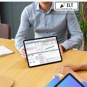 May include: A tablet displaying a spreadsheet with charts and data is held by a person wearing a blue shirt. The tablet is on a wooden table. The text "ELT Everyday Lean Tools" is visible in the upper right corner.