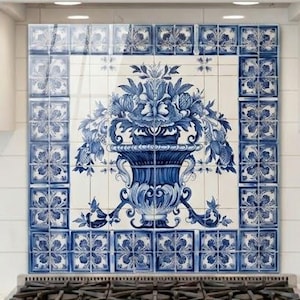 May include: Kitchen backsplash featuring blue and white floral tile design. The tile is centered above a stainless steel gas range. A matching blue and white ceramic jar with a lid and spoon sits on the countertop.