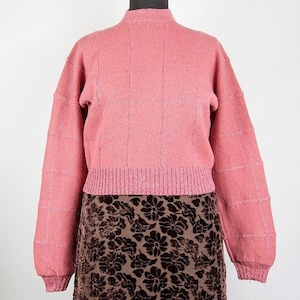 Op de afbeelding: Een roze getailleerde trui met een geruit patroon. De trui heeft lange mouwen en een hoge hals.