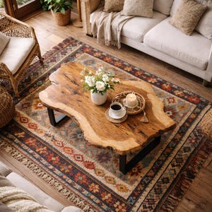 Peut inclure: Une table basse en bois aux bords naturels et aux pieds en métal noir, posée sur un tapis à motifs. La table présente un vase de fleurs, une tasse de café et une bougie. Le tapis présente un motif géométrique coloré avec une frange.