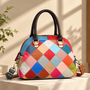 Puede incluir: Un bolso de mano con forma de cúpula que presenta un patrón de parches de diamantes multicolor en tonos rojo, azul, rosa, naranja y beige. El bolso incluye asas de cuero marrón oscuro, herrajes de metal dorado y una correa ajustable extraíble.