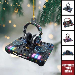Könnte beinhalten: Ein hängendes Ornament in Form eines DJ-Controllers mit darauf platzierten Kopfhörern. Der schwarze Controller verfügt über bunte Tasten, Regler und den auf der Vorderseite aufgedruckten Text DJ JOHNNY. Kleine bunte Lichterketten umgeben das Gerät.