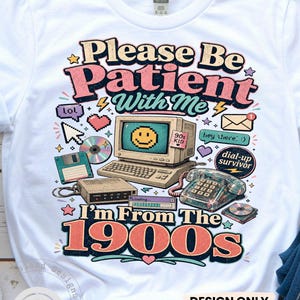 Puede incluir: Una camiseta blanca con un gráfico retro y el texto "Please Be Patient With Me I'm From The 1900s". El diseño incluye un ordenador antiguo, un teléfono, un disquete, un CD y varios iconos de los años 90 en rosa, azul y amarillo.