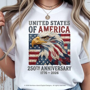 Op de afbeelding: Wit T-shirt met een patriottisch ontwerp ter viering van de 250e verjaardag van de Verenigde Staten. De afbeelding toont een adelaar, de Amerikaanse vlag en de tekst "UNITED STATES OF AMERICA" en "250TH ANNIVERSARY 1776-2026".