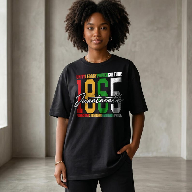 K&ouml;nnte beinhalten: Schwarzes T-Shirt mit dem Wort "Juneteenth" in Schreibschrift und den Zahlen "1865" in fetter, farbiger Schrift. Das Shirt zeigt auch die W&ouml;rter "Unity Legacy Power Culture" und "Freedom Strength Heritage Pride".
