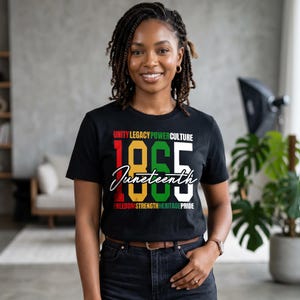 K&ouml;nnte beinhalten: Schwarzes T-Shirt mit dem Text "UNITY LEGACY POWER CULTURE" &uuml;ber den Zahlen "1865" und dem Wort "Juneteenth" in Schreibschrift. Unter den Zahlen steht der Text "FREEDOM STRENGTH HERITAGE PRIDE". Das T-Shirt wird von einer Person getragen.