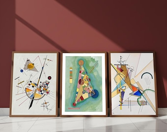 May include: Three framed abstract art prints. Each print features geometric shapes and lines in a variety of colors, including yellow, blue, red, and black. The frames are a warm brown color, and the artwork is displayed against a maroon wall.