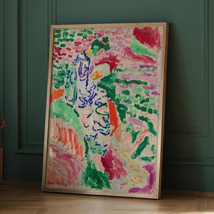 May include: A framed abstract painting with a wooden frame. The artwork features a vibrant mix of colors, including green, red, blue, and pink. The style appears to be impressionistic, with visible brushstrokes and a textured appearance. The artist's signature is visible in the bottom left corner.