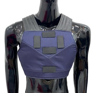 May include: A dark blue chest protector vest featuring five rectangular black hook-and-loop fastener patches on the front panel and wide, ribbed black shoulder straps that extend over the upper torso area for a secure fit.