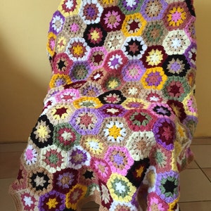 May include: A colorful crocheted blanket with a hexagonal pattern in shades of pink, purple, yellow, brown, and green.