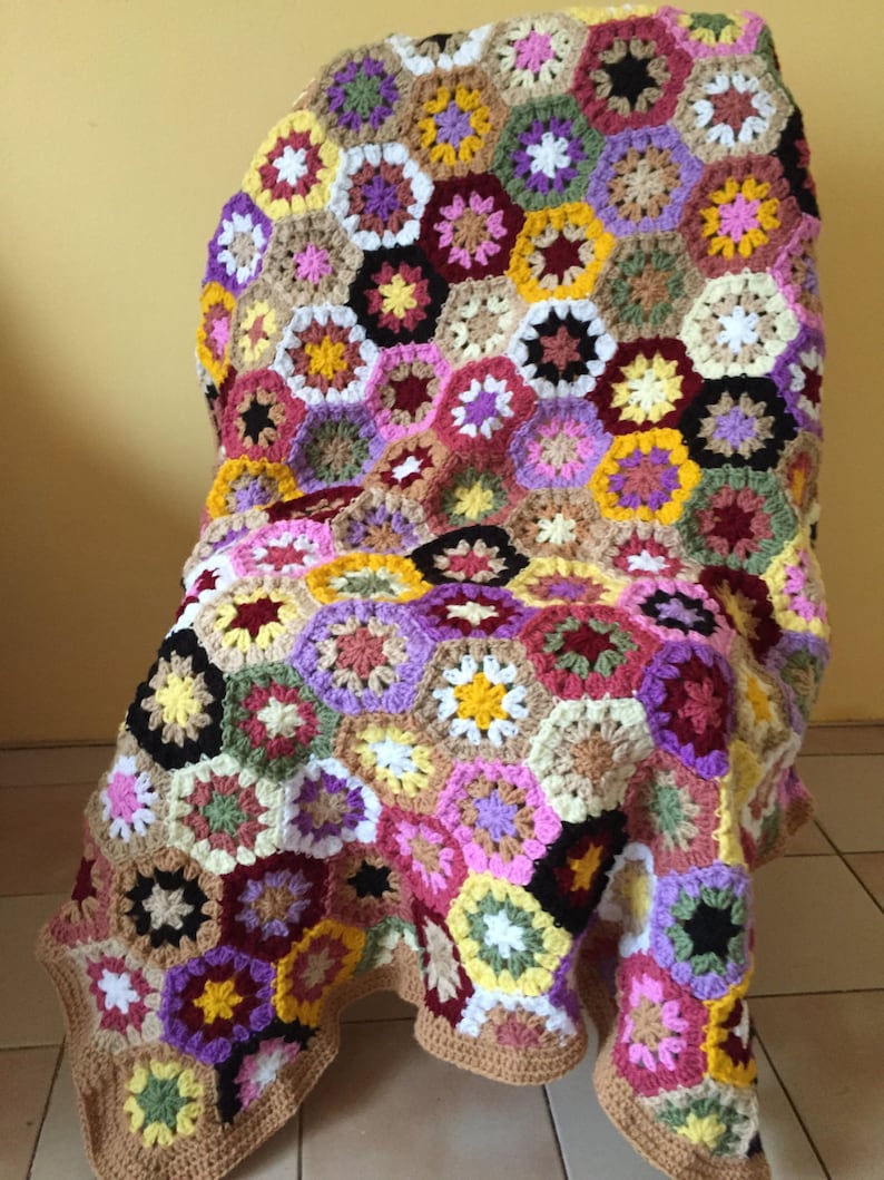 May include: A colorful crocheted blanket with a hexagonal pattern in shades of pink, purple, yellow, brown, and green.