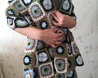 May include: A crocheted shawl made of granny squares in black, white, brown, green, and blue.