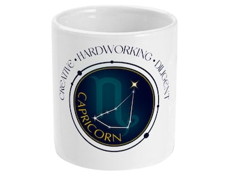 May include: White ceramic mug featuring a Capricorn zodiac design. The design includes the Capricorn symbol, constellation, and the word "Capricorn" in gold lettering, surrounded by the words "Creative, Hardworking, Diligent."