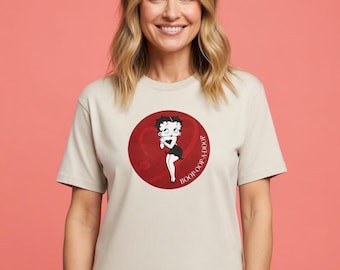 May include: Beige t-shirt featuring a red circle with a Betty Boop graphic. The graphic shows Betty Boop in a black dress and white gloves. The text "BOOP-OOP-A-DOOP" is printed around the circle.