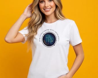 May include: White t-shirt featuring a Virgo constellation design within a circular frame. The design includes the word "Virgo" and the words "Perceptive, Dedicated, Thoughtful". The shirt is worn by a person with long blonde hair.