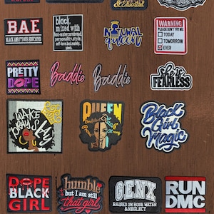 May include: A collection of rectangular, circular, and shaped embroidered patches featuring various slogans and graphics. Text includes phrases like Karma Club, Natural Queen, Black Girl Magic, GenX, and Run DMC, rendered in diverse fonts and colors.