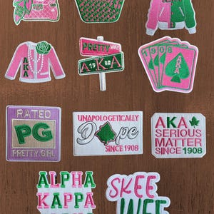 May include: A collection of eleven embroidered patches featuring pink and green designs, including a handbag, tote, varsity jacket, blazer, street signs, playing cards, and text reading AKA, PG, Dope, and Skee Wee.