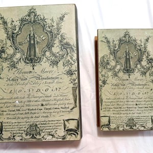 May include: Two antique boxes with ornate illustrations and text. The boxes feature a central figure in a decorative frame, surrounded by floral and animal motifs. The text includes the name "Thomas Moore" and the location "London".