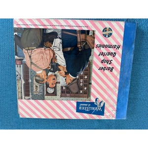 May include: A vintage album cover titled "Barber Shop Quartet Harmonies" with a pink and white striped border. The cover features an illustration of four men in a barbershop setting. The Wurlitzer logo is visible.