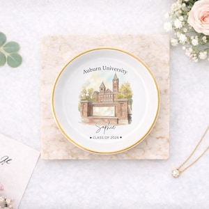 May include: A white ceramic trinket dish with a gold rim, featuring a watercolor illustration of Auburn University. The dish is personalized with the name "Sophie" and "CLASS OF 2026".