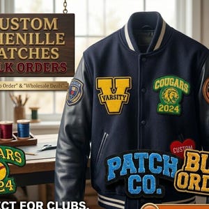 Op de afbeelding: Een marineblauwe varsity jas met zwarte leren mouwen en meerdere geborduurde patches. De patches bevatten de tekst "Varsity", "Cougars 2024" en "Patch Co.". Een houten bord erboven leest "Custom Chenille Patches Bulk Orders".