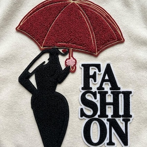 Könnte beinhalten: Schwarze Silhouette einer Frau, die einen roten Regenschirm mit goldenen Verzierungen hält. Das Wort "FASHION" ist in schwarzen Blockbuchstaben mit weißen Konturen geschrieben. Das Bild befindet sich auf weißem Hintergrund.