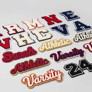 Puede incluir: Surtido de parches de letras universitarias en varios colores. Incluye letras rojas, azul marino, blancas y doradas. Algunos parches deletrean palabras como "Athletic" y "Varsity", mientras que otros son letras individuales o el n&uacute;mero "24".