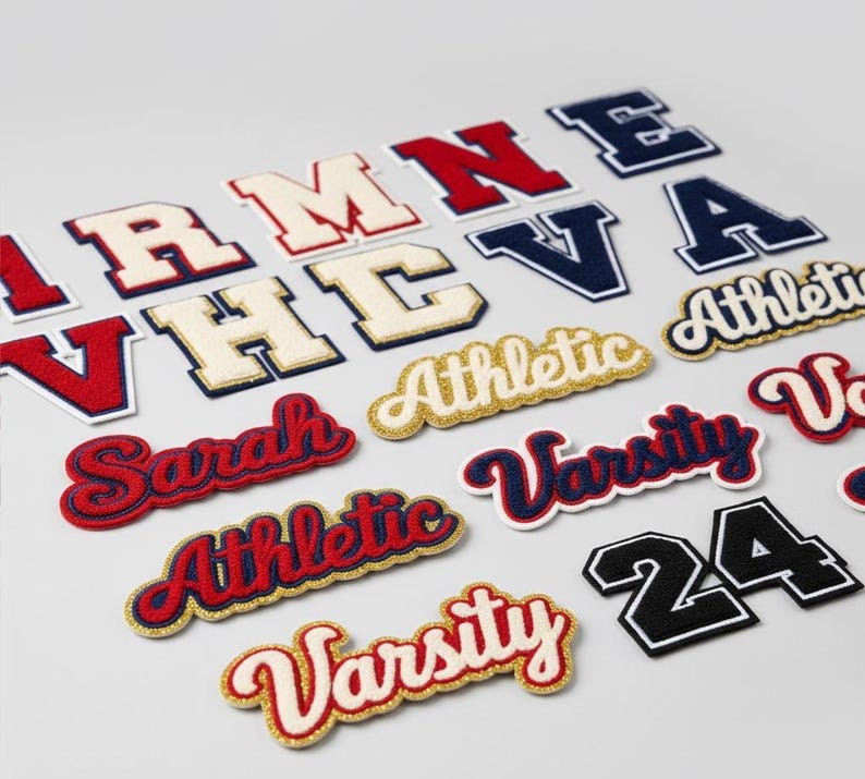 Puede incluir: Surtido de parches de letras universitarias en varios colores. Incluye letras rojas, azul marino, blancas y doradas. Algunos parches deletrean palabras como "Athletic" y "Varsity", mientras que otros son letras individuales o el n&uacute;mero "24".