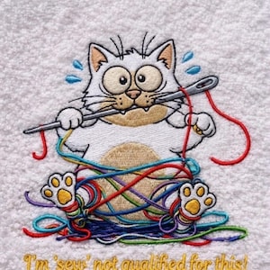 Può includere: Asciugamano bianco ricamato con un gatto dei cartoni animati impigliato in fili colorati, che tiene un ago e un filo. Il gatto ha grandi occhi e gocce di sudore, con il testo "I'm 'sew' not qualified for this!"