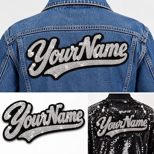 May include: A blue denim jacket and a black sequin jacket, each featuring a custom patch with the text YourName in silver rhinestones on a black background. The script lettering is outlined in a bold, curved style with sparkling crystal accents.