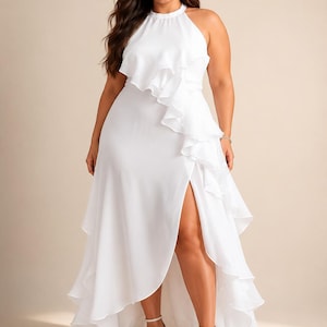 May include: A floor-length white sleeveless dress featuring a high halter neckline, a cascading ruffle detail running diagonally from the bodice to the hem, and a high side slit that reveals the leg. The skirt has a layered, flowing silhouette.