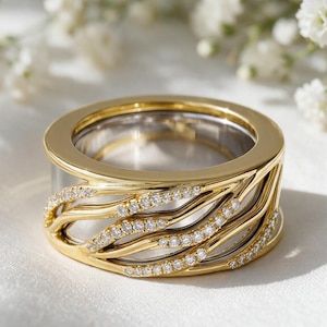 May include: A wide band ring featuring a polished gold exterior with a layered, wave-like design. The gold curves are accented with small, clear, sparkling stones set along the edges, revealing a smooth, silver-toned inner band beneath the structure.