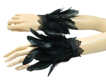 May include: A pair of black feather and lace wrist cuffs. The cuffs are made of black feathers and black lace. The cuffs are shown on a pair of mannequin arms.