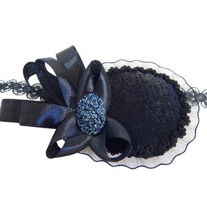 May include: A black eye patch with a black satin bow and a blue rhinestone embellishment. The eye patch is trimmed with black lace.