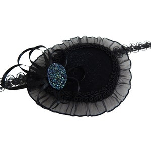 May include: A black eye patch with a lace trim and a sparkly blue jewel accent. The eye patch is made of velvet and has a ruffled edge.