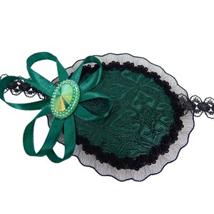 May include: A green eye patch with a black lace trim and a green satin bow with a sparkly green jewel in the center.