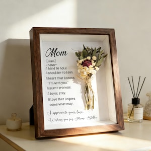Może przedstawiać: Oprawiona grafika z ciemnobrązową drewnianą ramą. Grafika przedstawia bukiet suszonych kwiatów i tekst z napisem "Mom" i definicją. Tekst zawiera zwroty takie jak "A hand to hold" i "I appreciate your love."