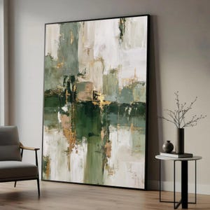 Könnte beinhalten: Abstrakte Kunstmalerei mit schwarzem Rahmen. Das Kunstwerk zeigt eine Mischung aus grünen, weißen und goldenen Farben. Das Gemälde hat ein strukturiertes Aussehen mit Pinselstrichen und Farbblöcken. Das Kunstwerk wird in einem modernen Wohnzimmer präsentiert.